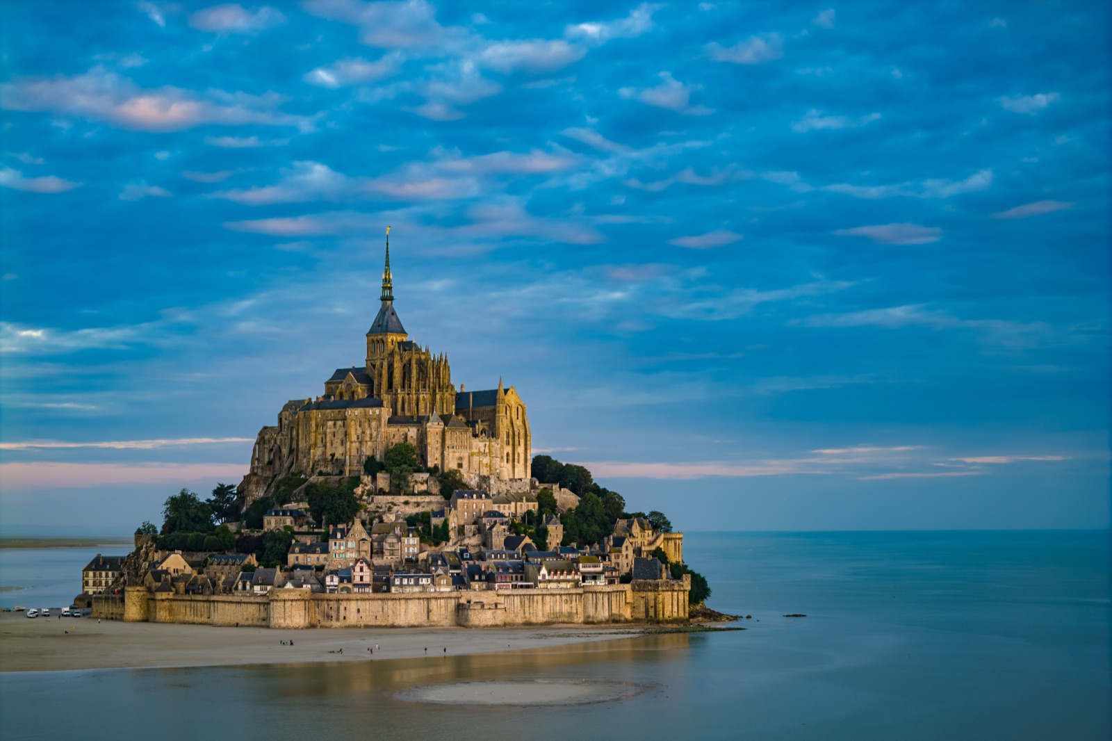 Mont-Saint-Michel surrounded by water, the abbey spire against a blue sky